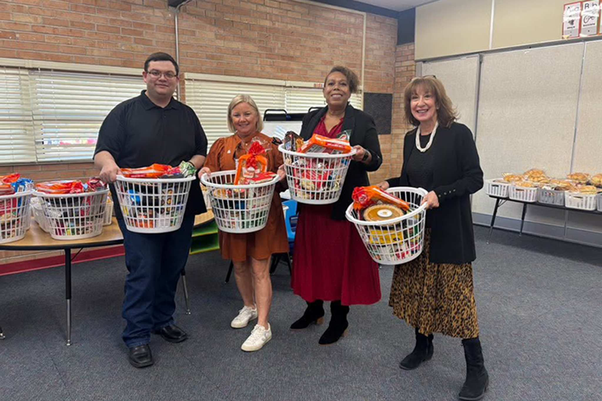 Four staff members hold up baskets of holiday meals