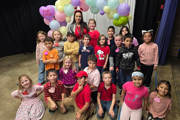 Students pose for a photo under a balloon arch