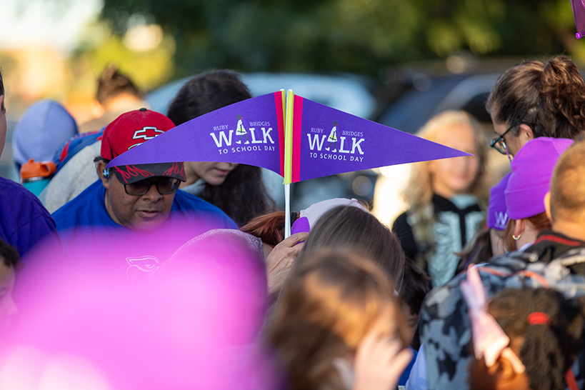 A woman holds up two purple Ruby Bridges Walk to School Day pennants