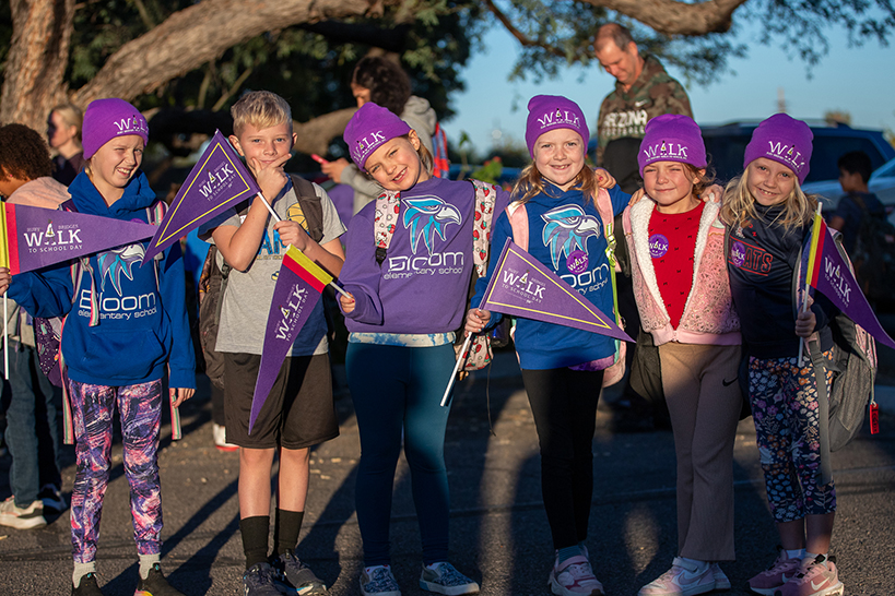 A group of students smile, holding their Ruby Bridges Walk to School Day pennants and wearing their purple beanies